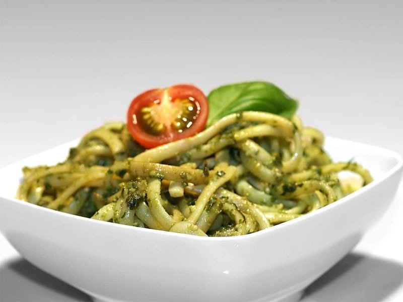 A plate of classic Italian basil pesto pasta tossed in vibrant green basil pesto sauce, garnished with fresh basil leaves and grated Parmesan cheese, capturing the fresh flavors and colors of traditional Italian cuisine.